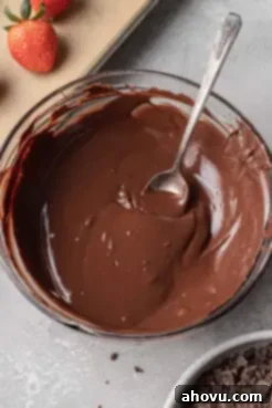 A glass mixing bowl containing tempered chocolate.