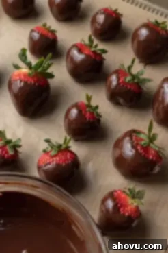Chocolate covered strawberries on a parchment paper lined baking tray.