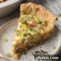 A delicious slice of golden-brown quiche on a speckled white plate, perfect for breakfast or brunch.