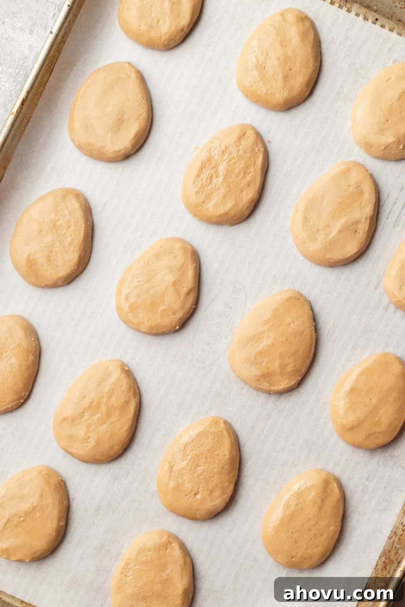 An overhead view of shaped peanut butter eggs on a baking tray.