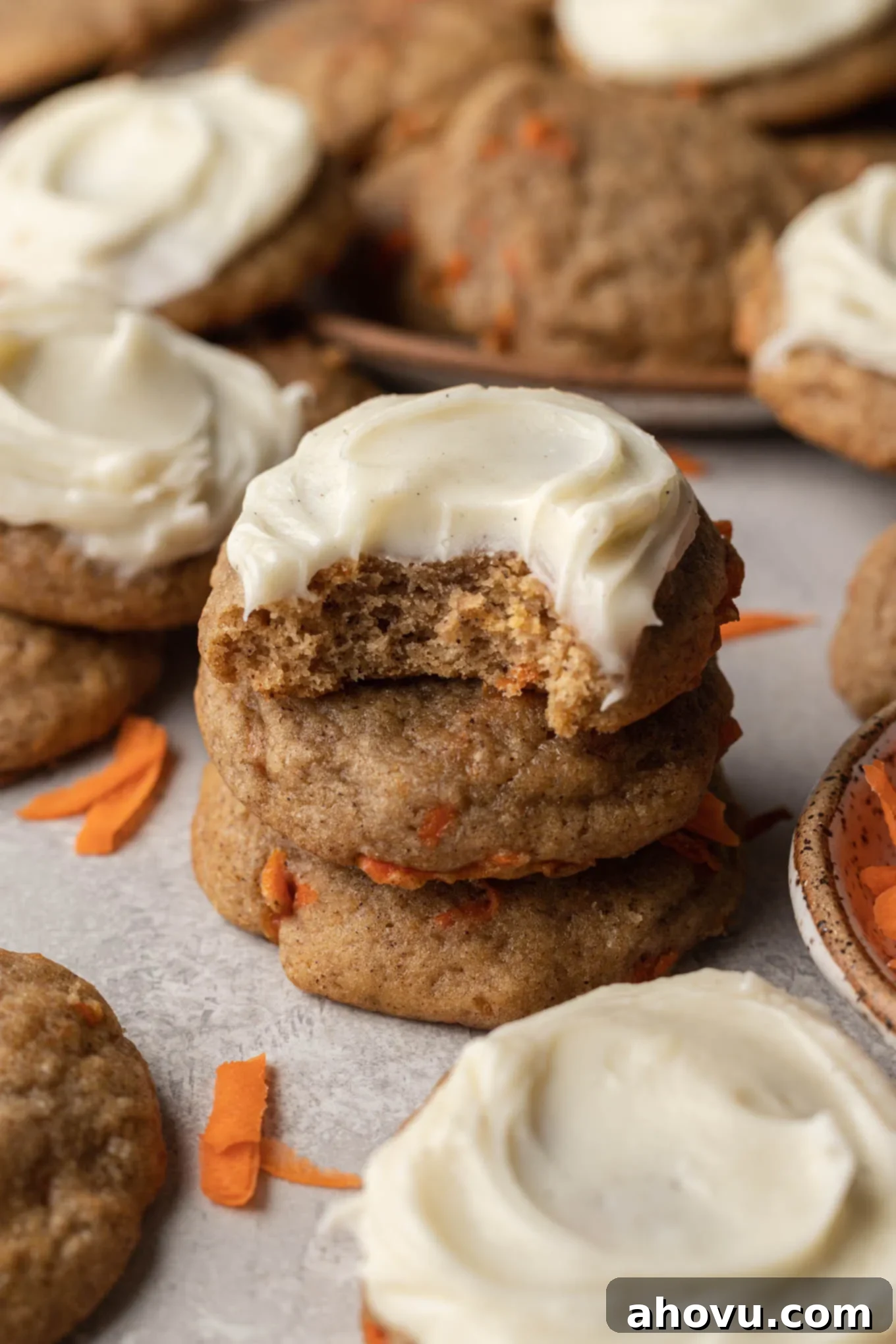 A stack of frosted carrot cake cookies, amongst other cookies, showcasing their inviting texture and rich frosting.