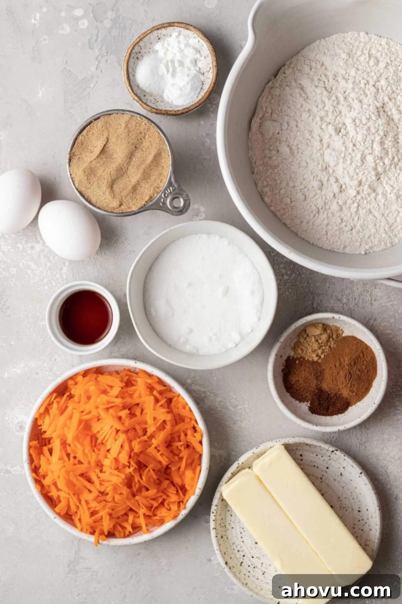 An overhead view of the essential ingredients laid out for making delicious carrot cake cookies, including flour, spices, butter, sugars, eggs, and carrots.
