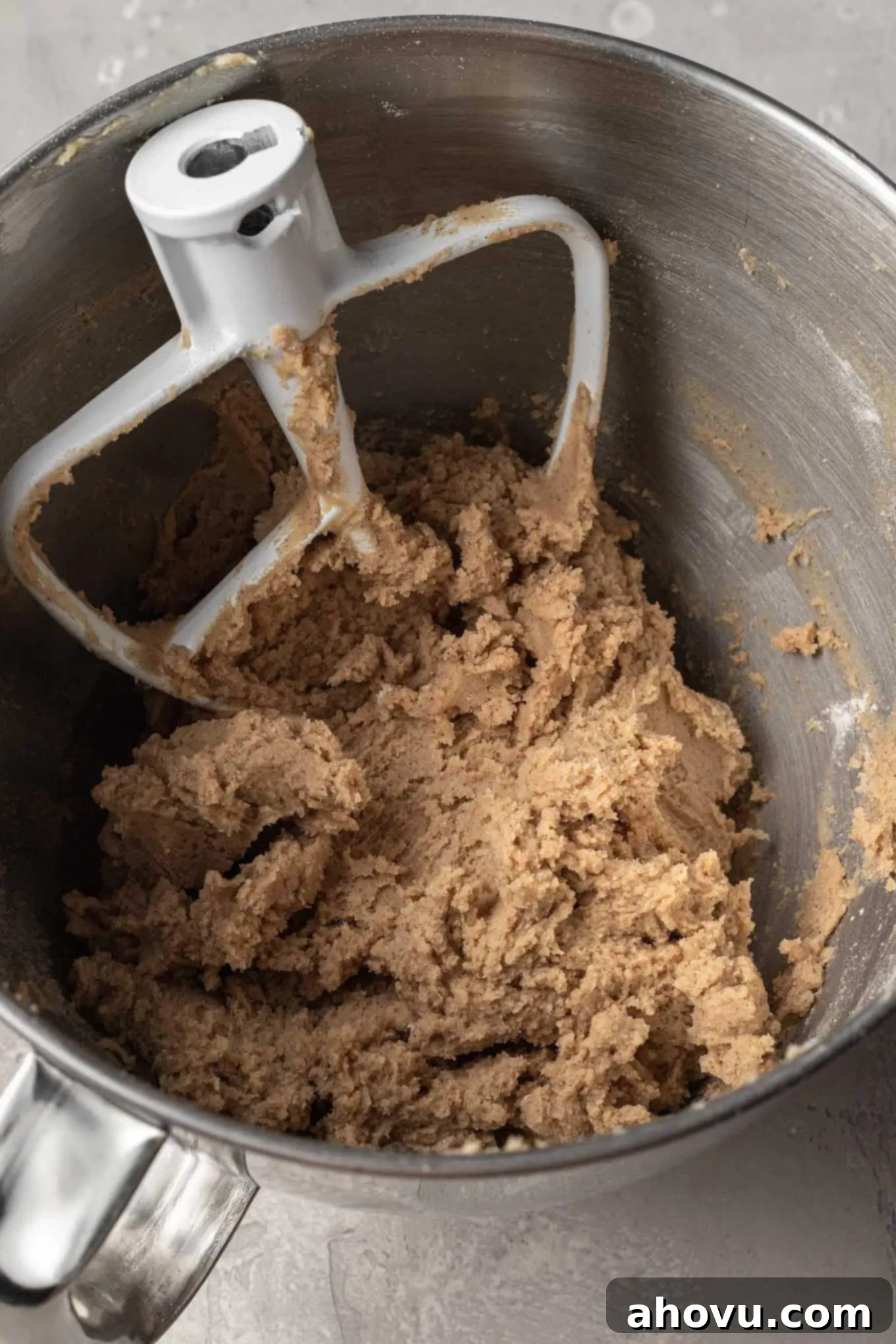 Freshly mixed carrot cake cookie dough in a metal mixing bowl, showing flecks of grated carrot and ready for chilling.