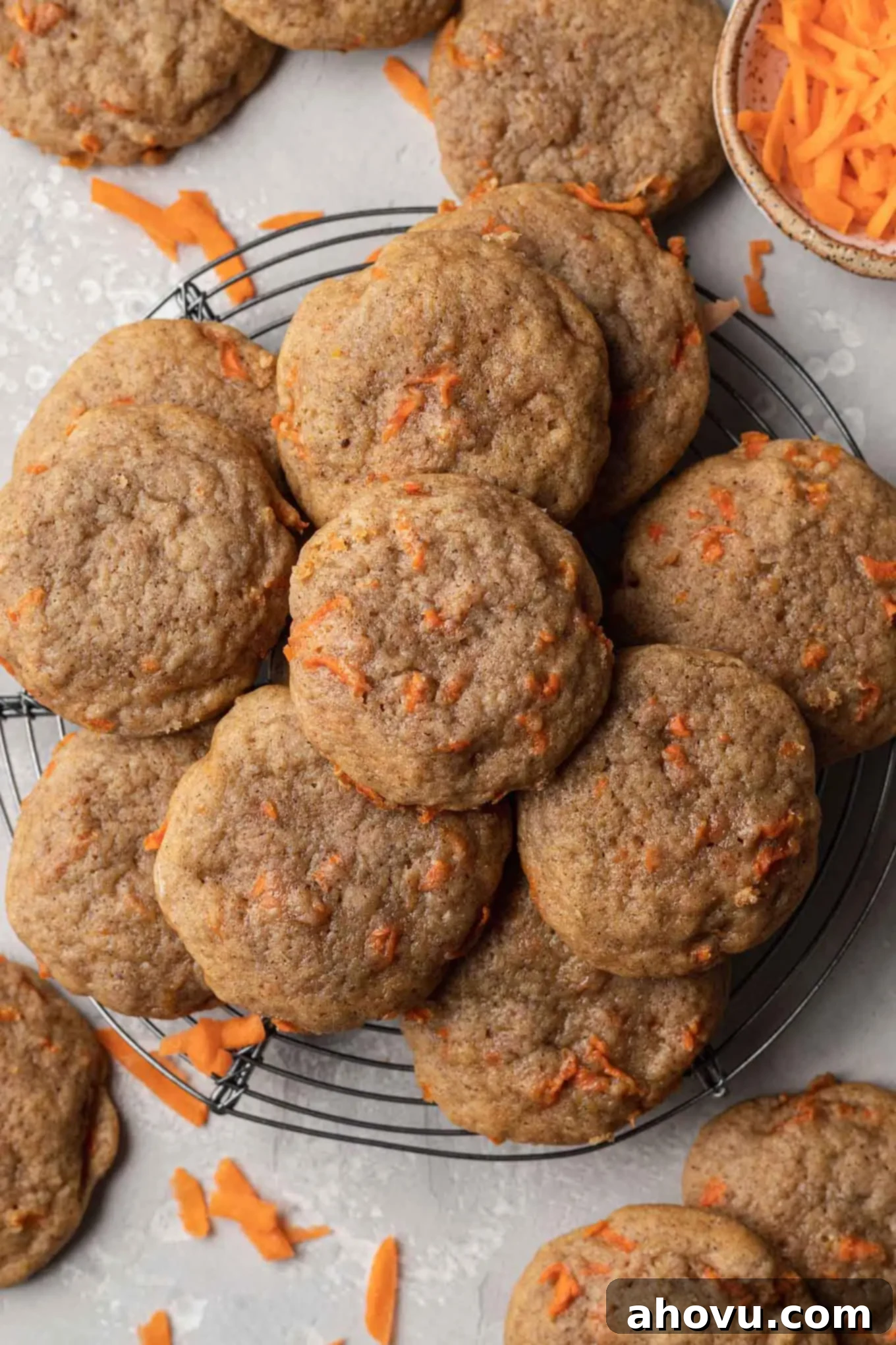An overhead view of unfrosted carrot cake cookies cooling on a wire rack, showing their perfectly baked texture.