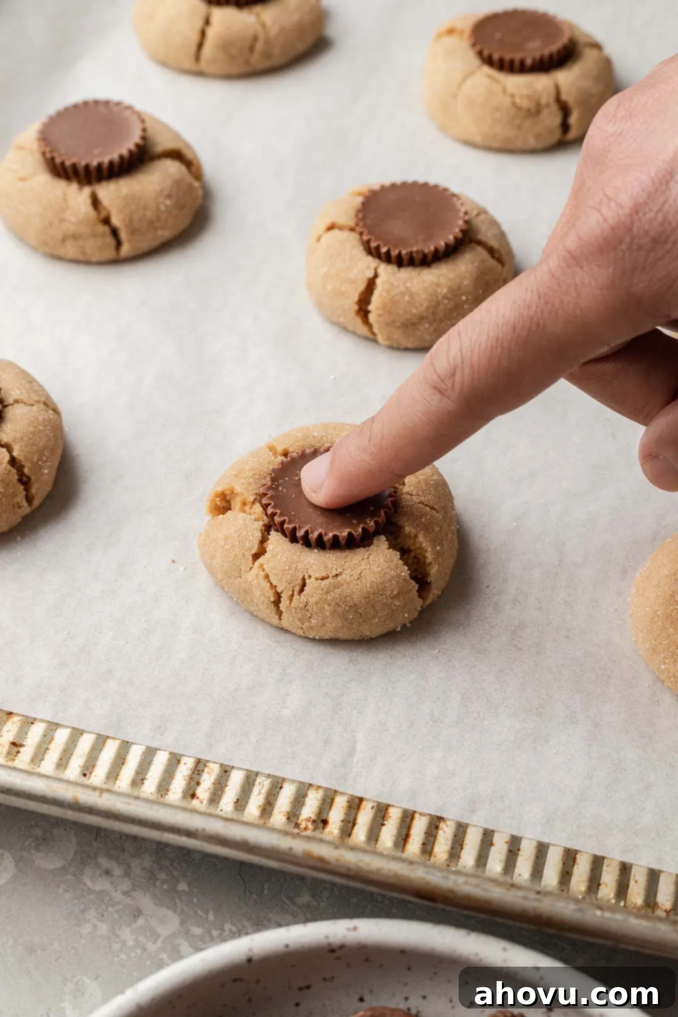 Mini peanut butter cups being pressed into baked peanut butter cookies. 