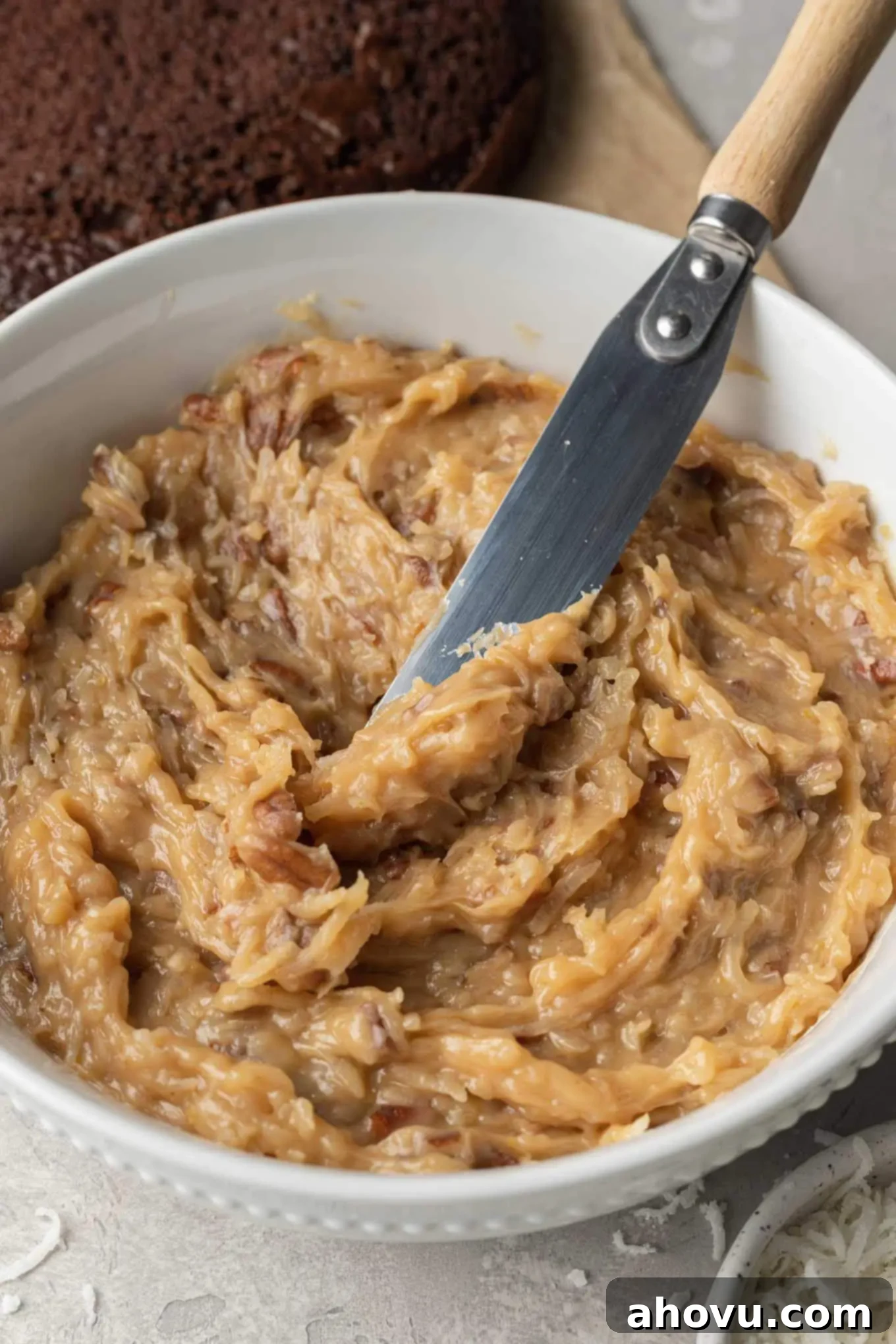 A large bowl of German chocolate cake frosting with an offset spatula, ready for use.