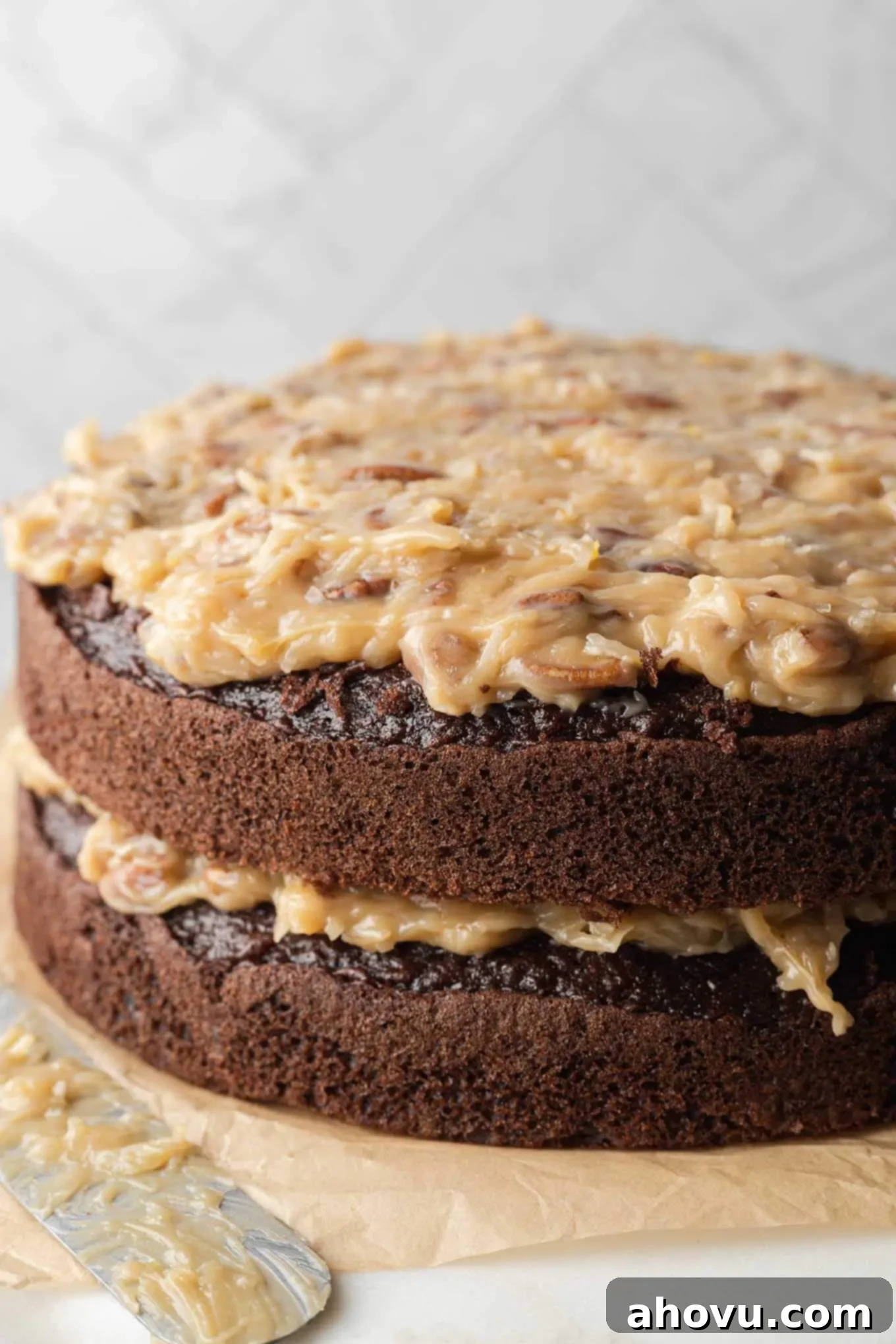 A side view of a beautifully layered German chocolate cake with homemade frosting and a drip.