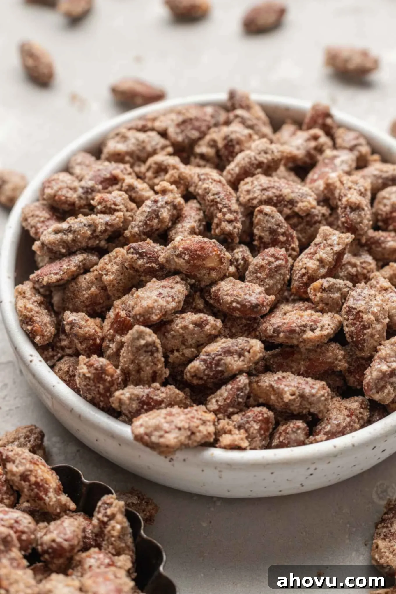 A generous serving of candied almonds piled high in a large decorative bowl, showcasing their abundance and appealing texture.