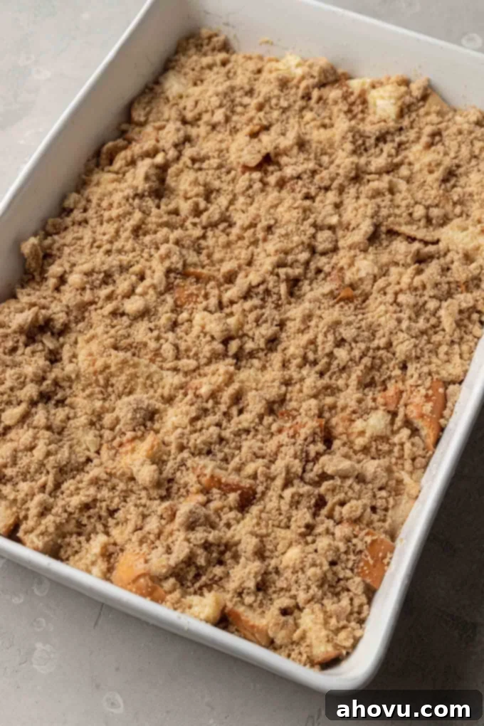 Sweet Morning French Toast Bake 7 Unbaked challah french toast casserole in a white baking dish with the crumb topping added.