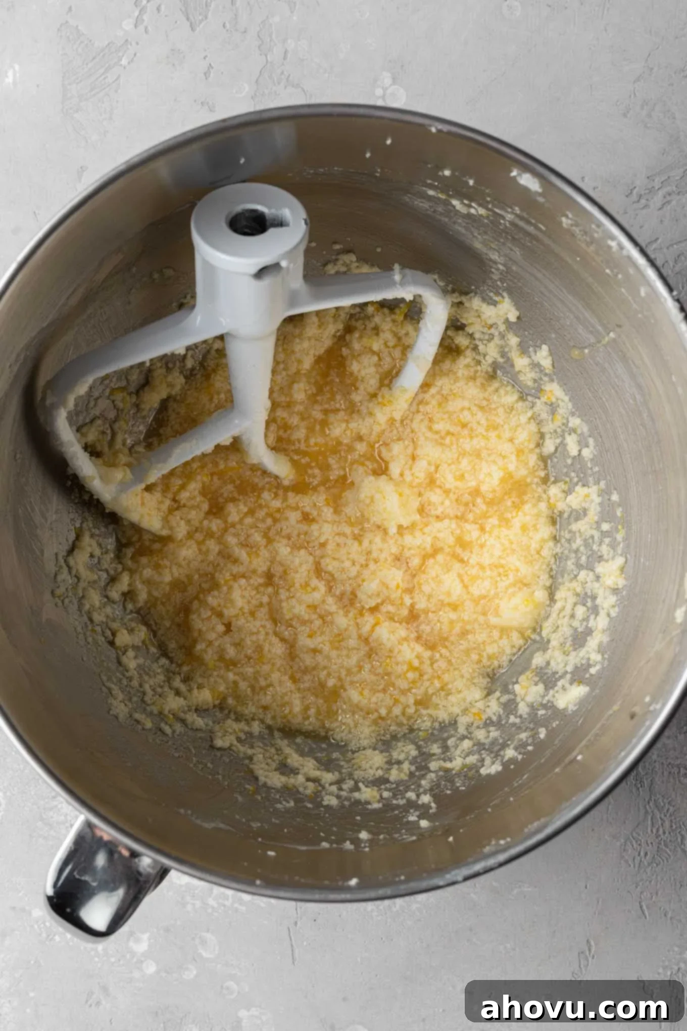 An overhead shot showcasing the addition of eggs, lemon juice, lemon zest, and vanilla extract to the creamed butter and sugar, forming the wet ingredients for the lemon cupcakes.