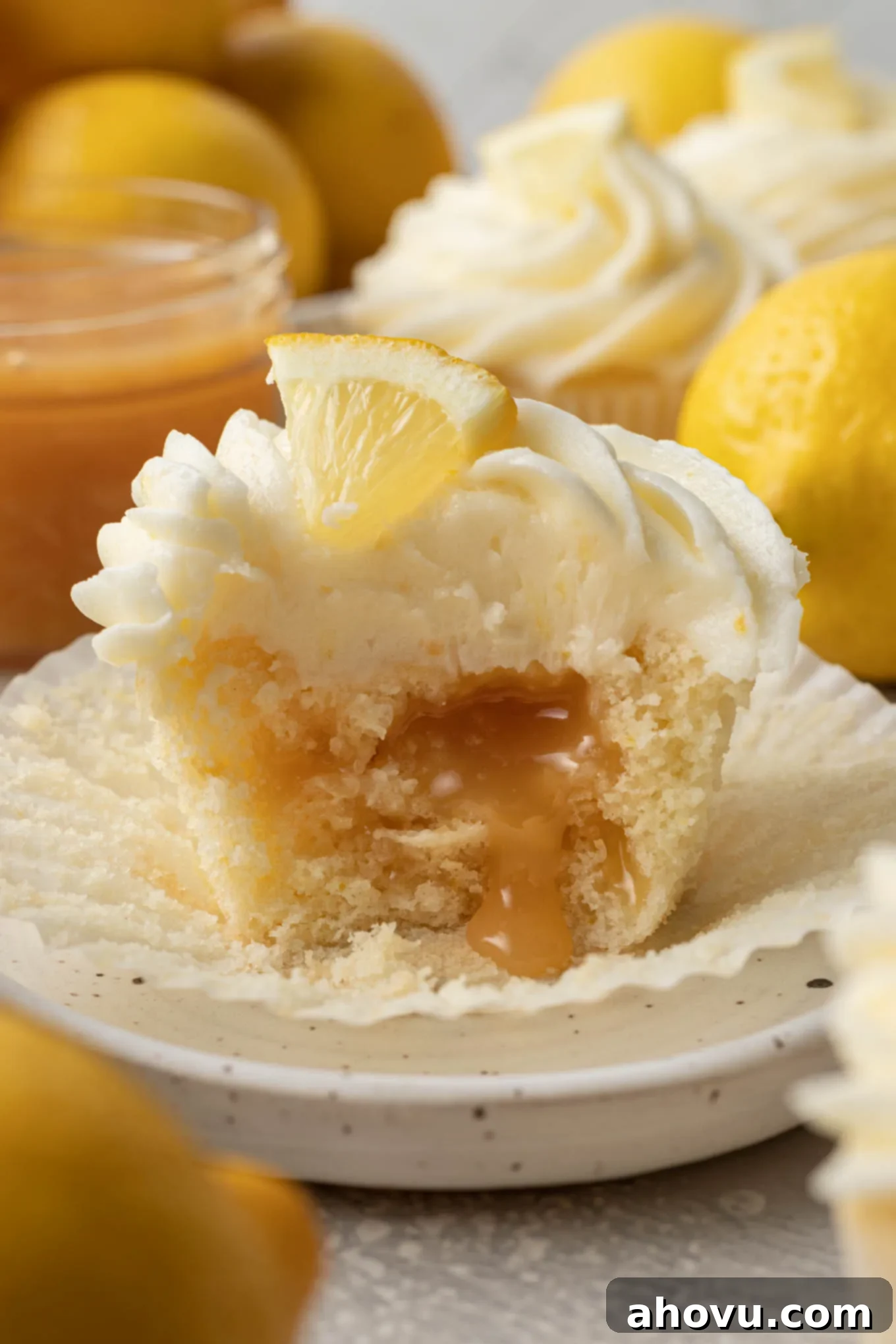 A mouth-watering close-up of a lemon curd filled cupcake with a bite taken out, revealing the luscious, golden lemon curd oozing tantalizingly from the center.