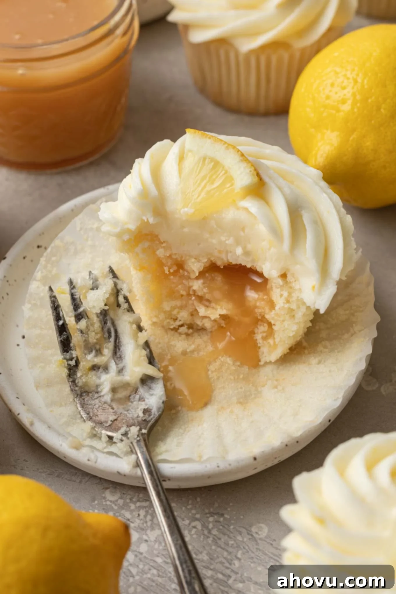 A delightful lemon curd cupcake served on a simple dessert plate, with a small piece missing, allowing the rich, tangy lemon curd to elegantly spill out.