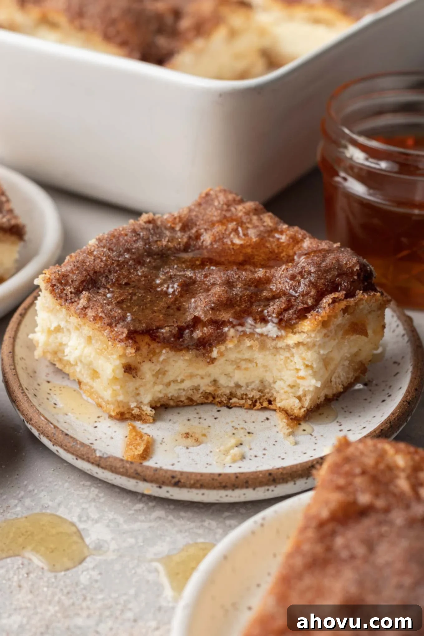 A sopapilla cheesecake bar on a speckled dessert plate, with a bite missing.