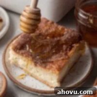 A slice of sopapilla cheesecake being drizzled with honey.