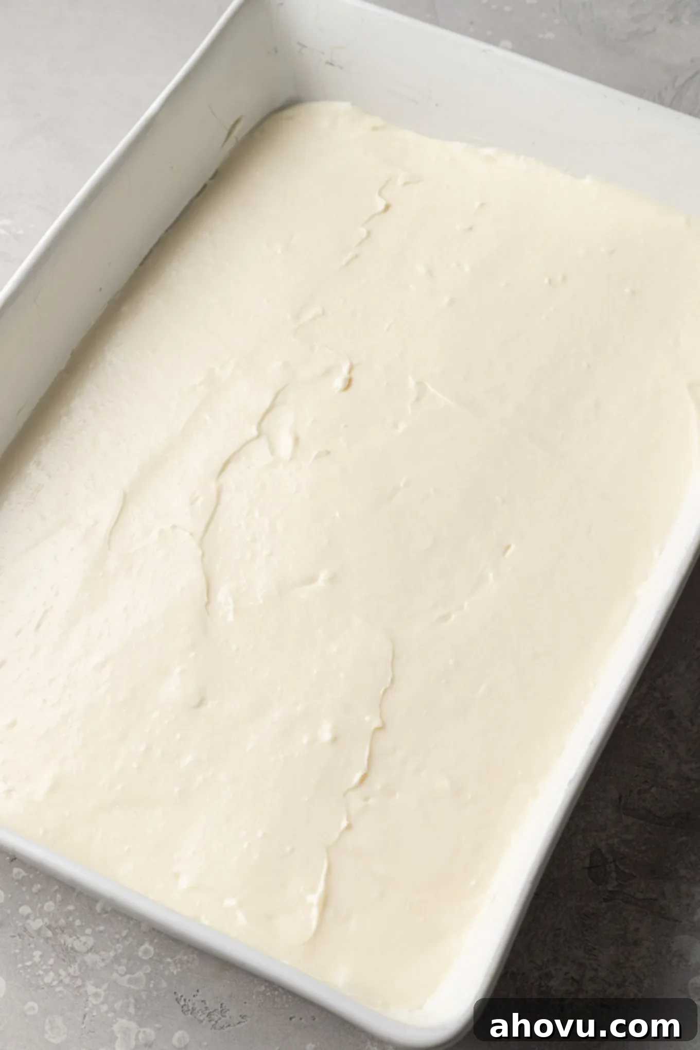 An overhead view of cheesecake filling smoothed into a 9x13-inch pan.