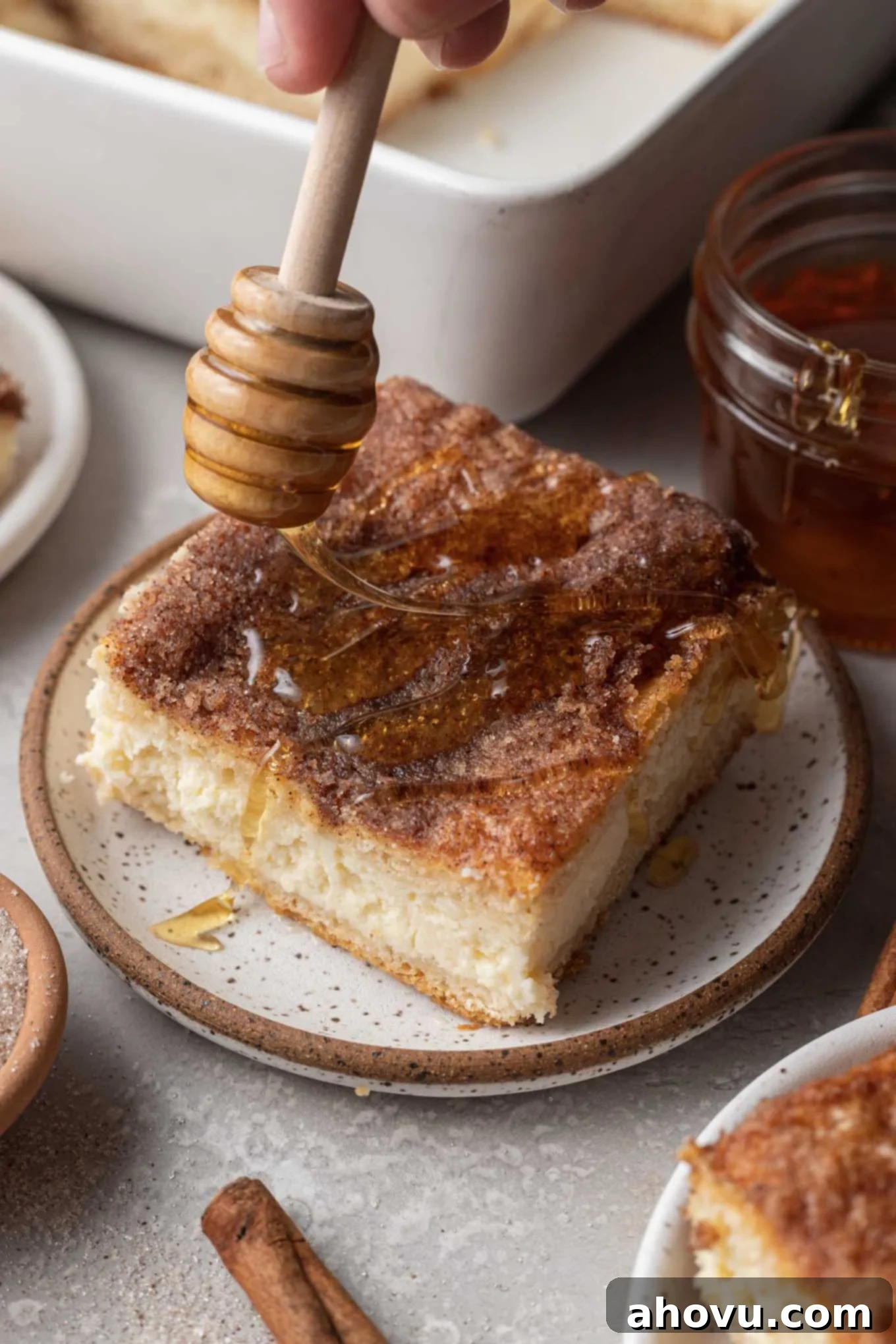 A slice of sopapilla cheesecake being drizzled with honey.