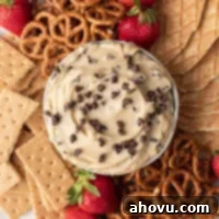 Dreamy Cookie Dough Dip 11 An overhead view of cookie dough dip in a bowl. The bowl is surrounded by pretzels, graham crackers, strawberries, and pieces of waffle cones.