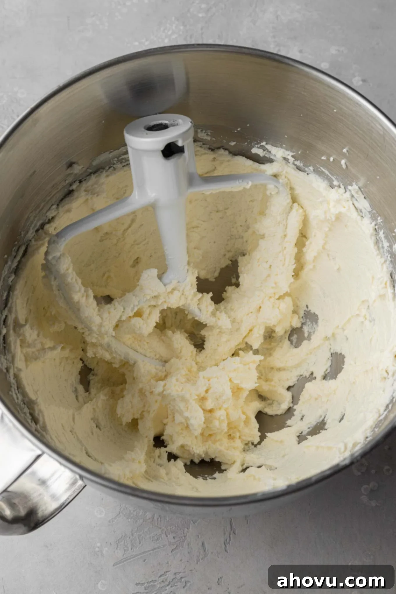 Dreamy Cookie Dough Dip 5 An overhead view of creamed butter and cream cheese in a mixing bowl, with a paddle attachment resting inside.