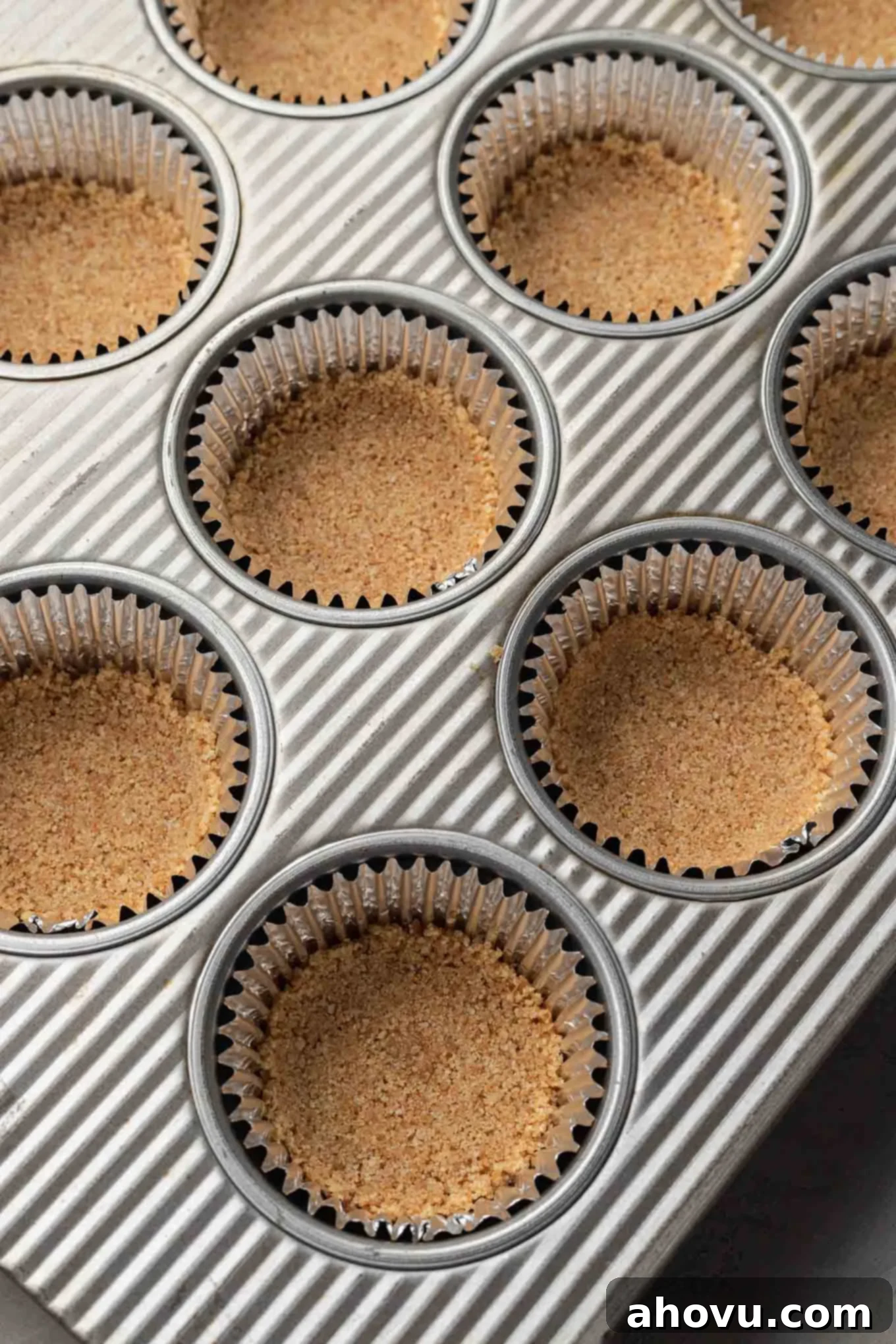 Muffin cups lined with cupcake liners and filled with a graham cracker crust. 