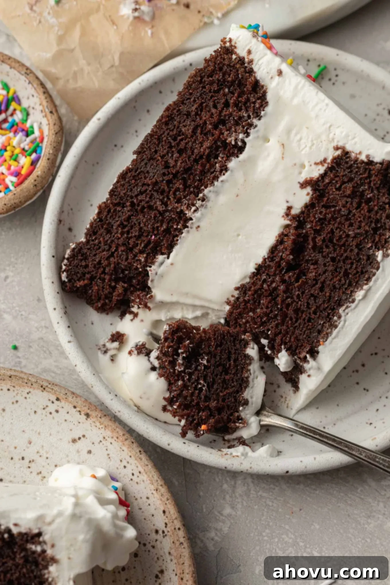 The Ultimate Homemade Ice Cream Cake 18 A perfectly sliced ice cream cake on a white speckled plate, with a fork poised to take a bite, highlighting its tempting layers.