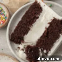 The Ultimate Homemade Ice Cream Cake 19 A slice of ice cream cake on a white plate. A fork with a piece of the cake is resting on the side, highlighting the delicious layers.