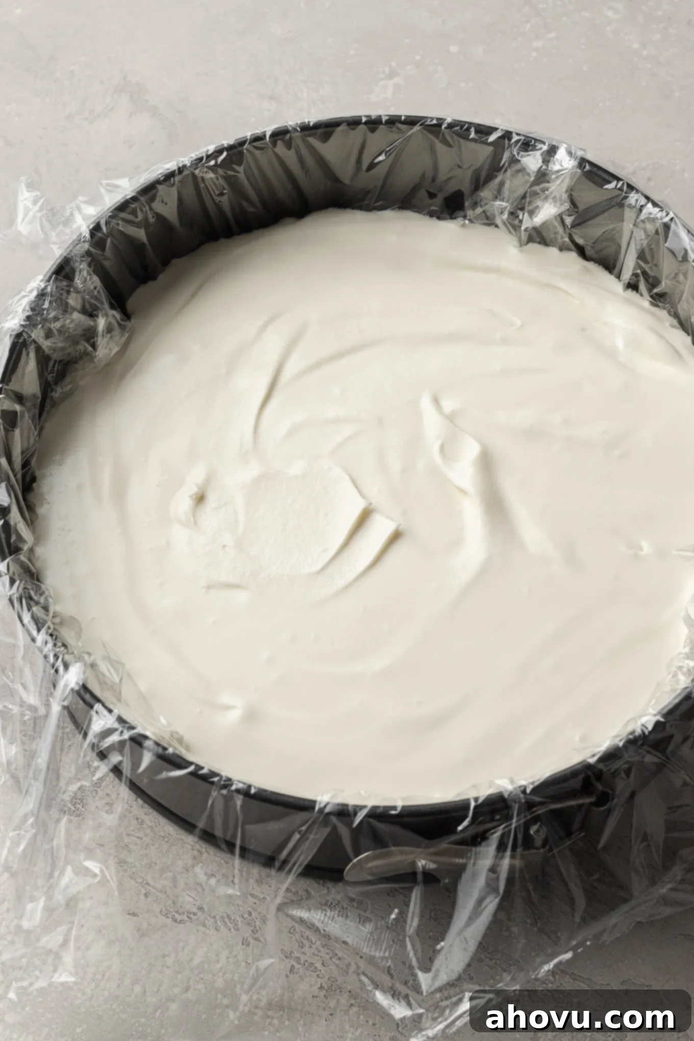 The Ultimate Homemade Ice Cream Cake 7 Smooth vanilla ice cream spread evenly into a springform pan that's been carefully lined with plastic wrap, ready for the freezer.