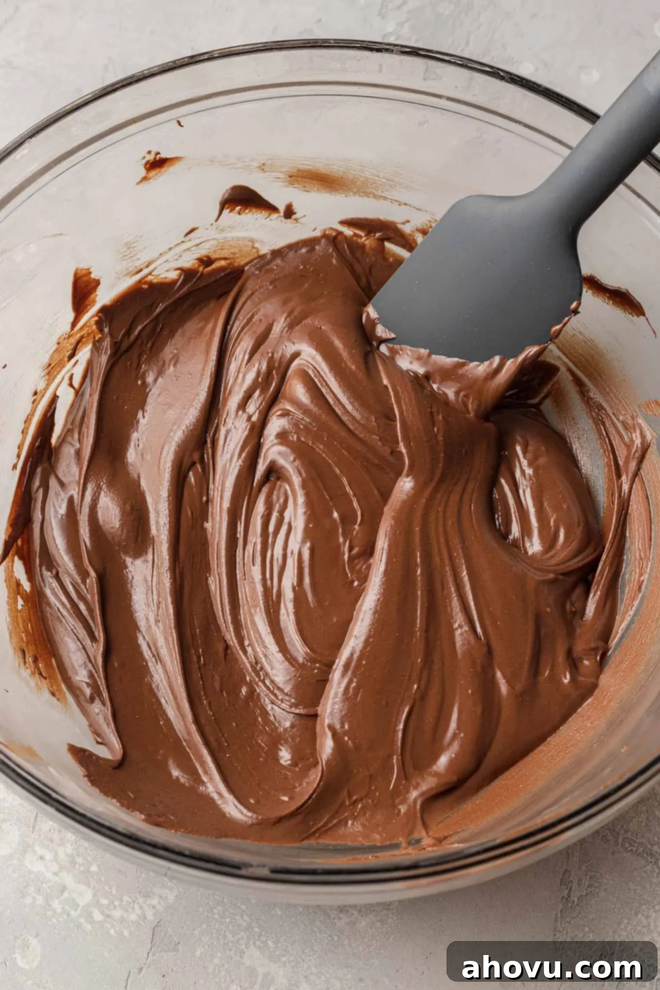 An overhead view of melted chocolate and peanut butter chips in a glass mixing bowl. 