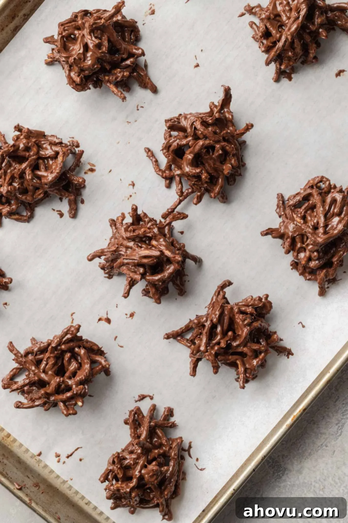 An overhead view of the haystack cookie mixture scooped onto a baking sheet lined with parchment paper.