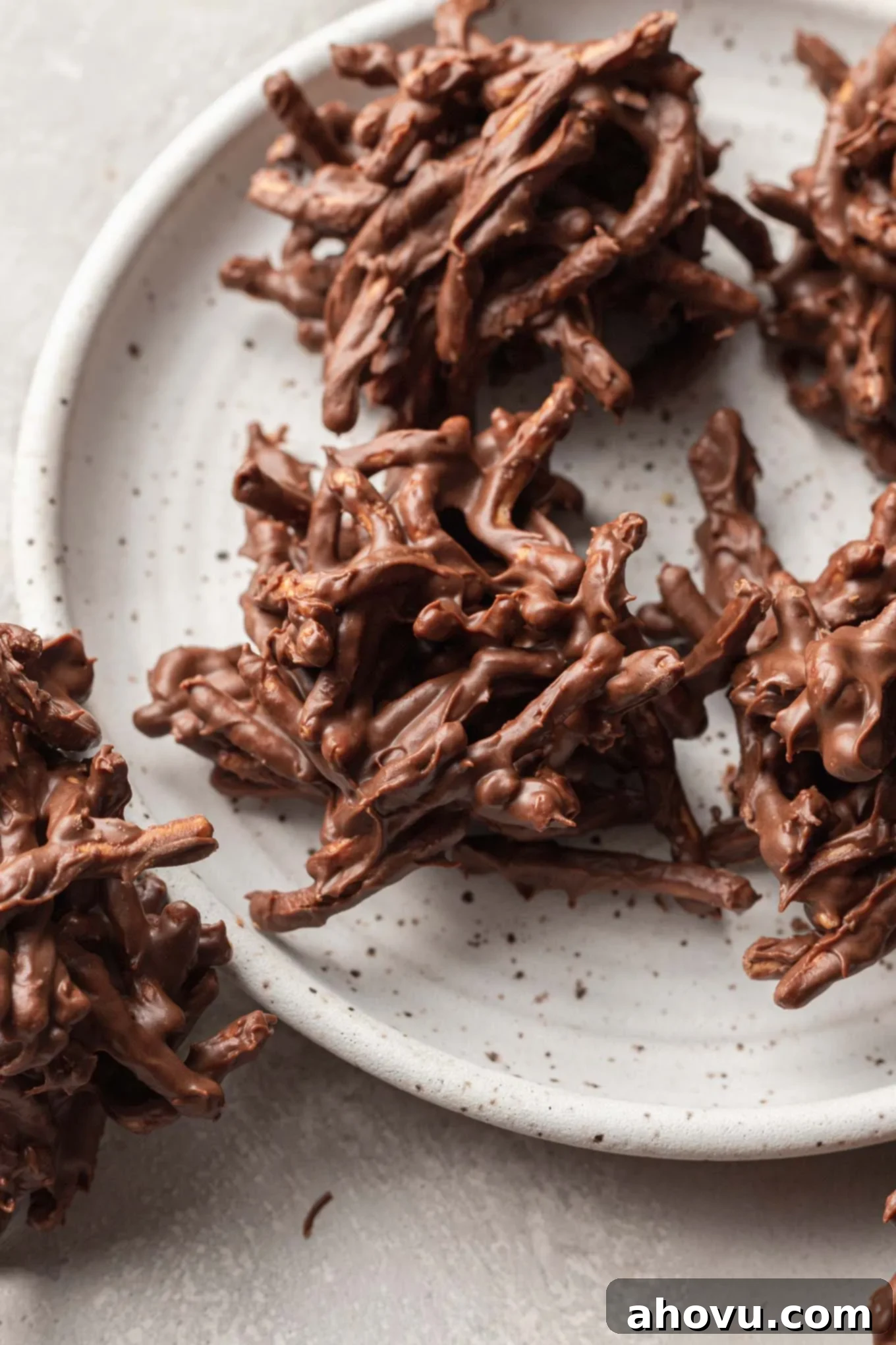 Plain haystack chocolate cookies on a white speckled plate. 