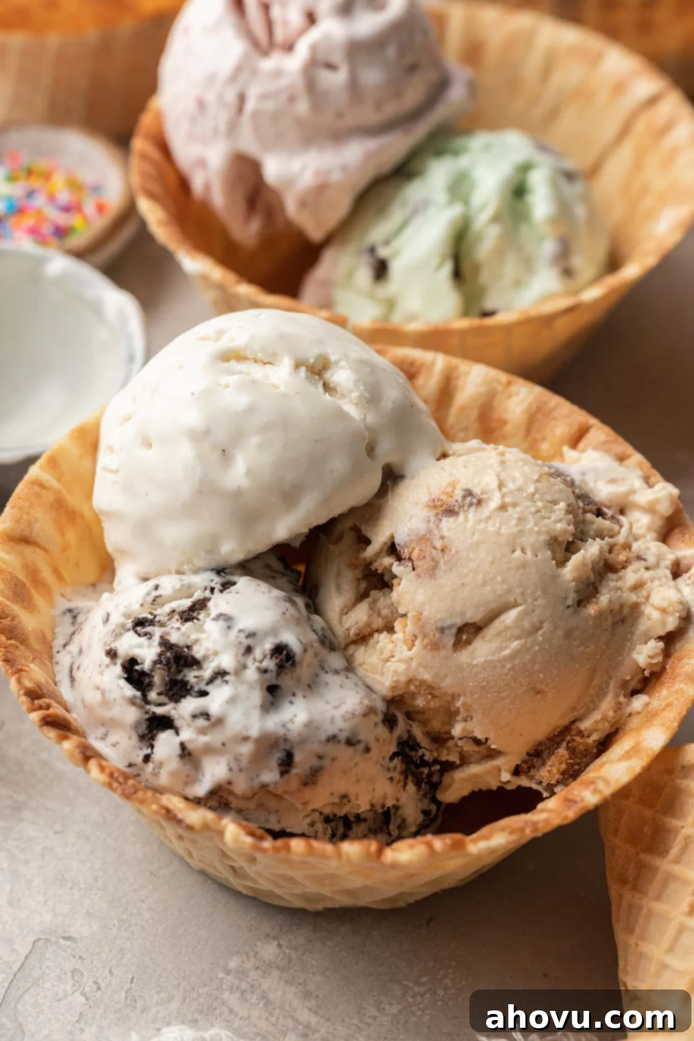 Two waffle cone bowls, one filled with classic vanilla no-churn ice cream and the other with a colorful strawberry variation, showcasing diverse flavor possibilities.