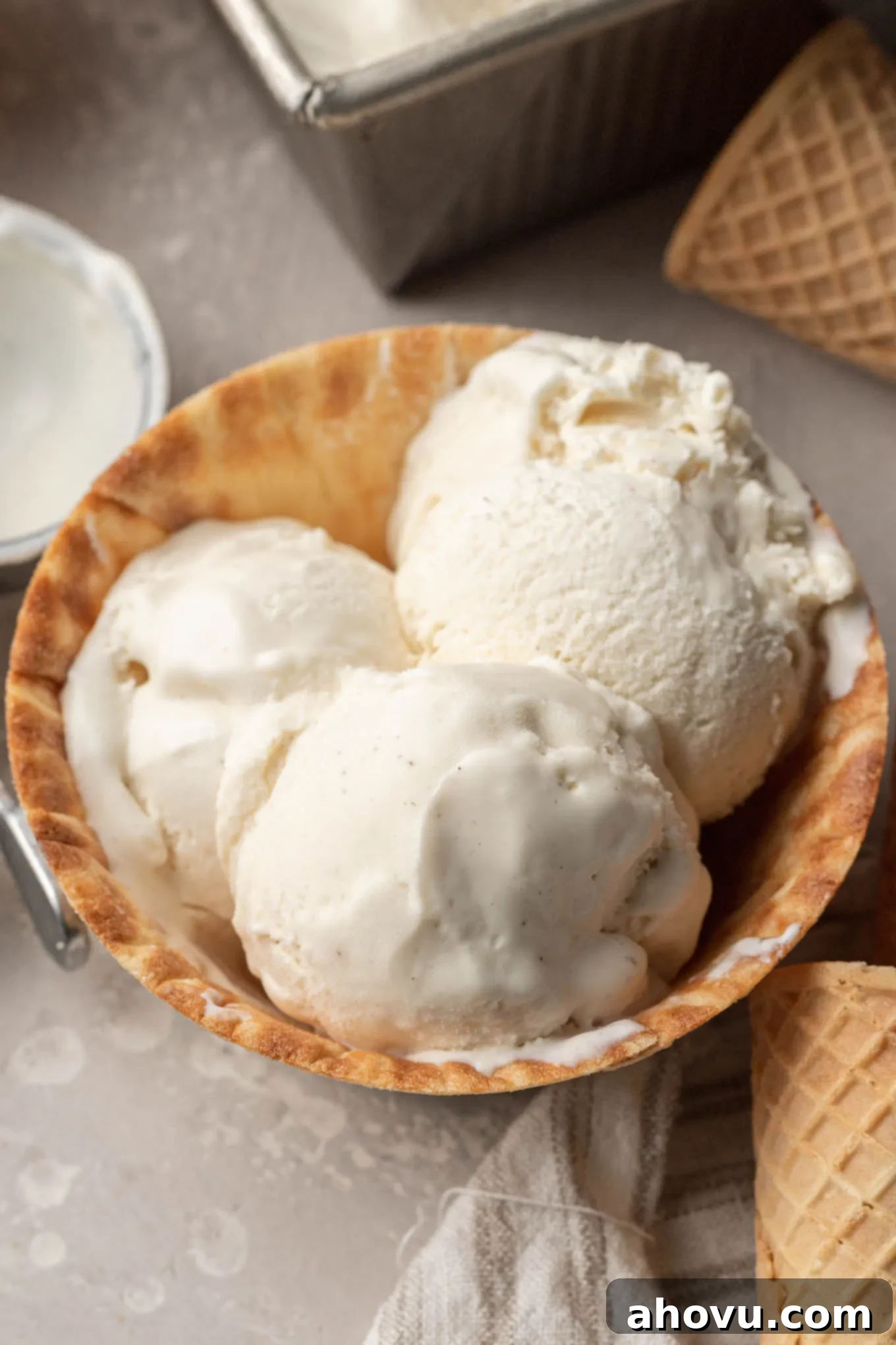 A crisp waffle cone bowl holds three perfect scoops of creamy vanilla no-churn ice cream, simple yet inviting.