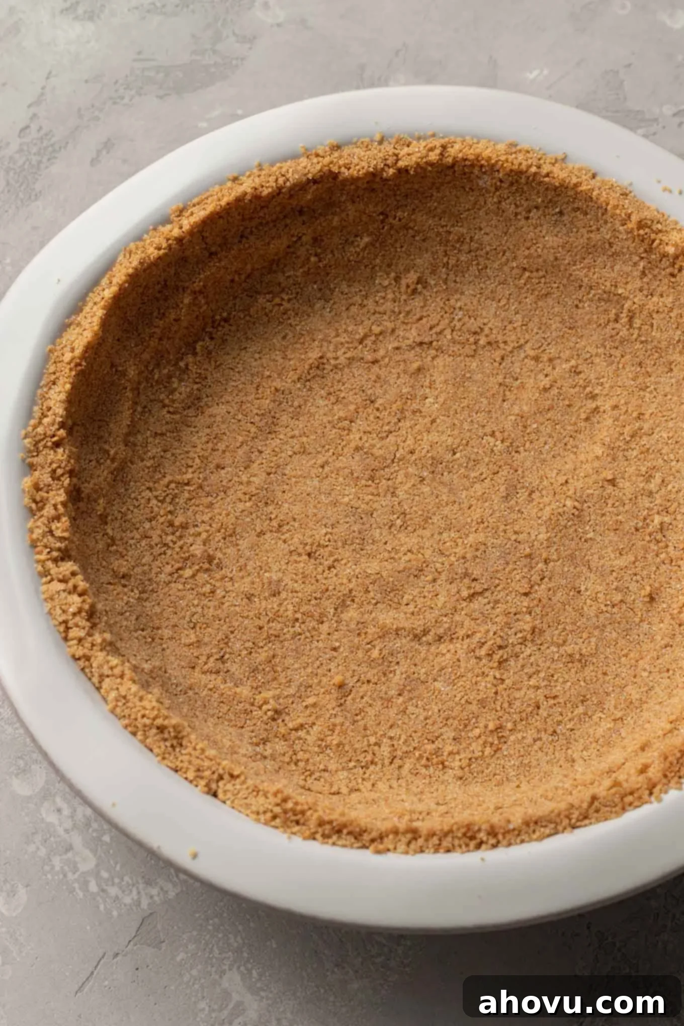 An overhead view of a perfectly pressed graham cracker crust awaiting its filling in a 9-inch pie plate. 