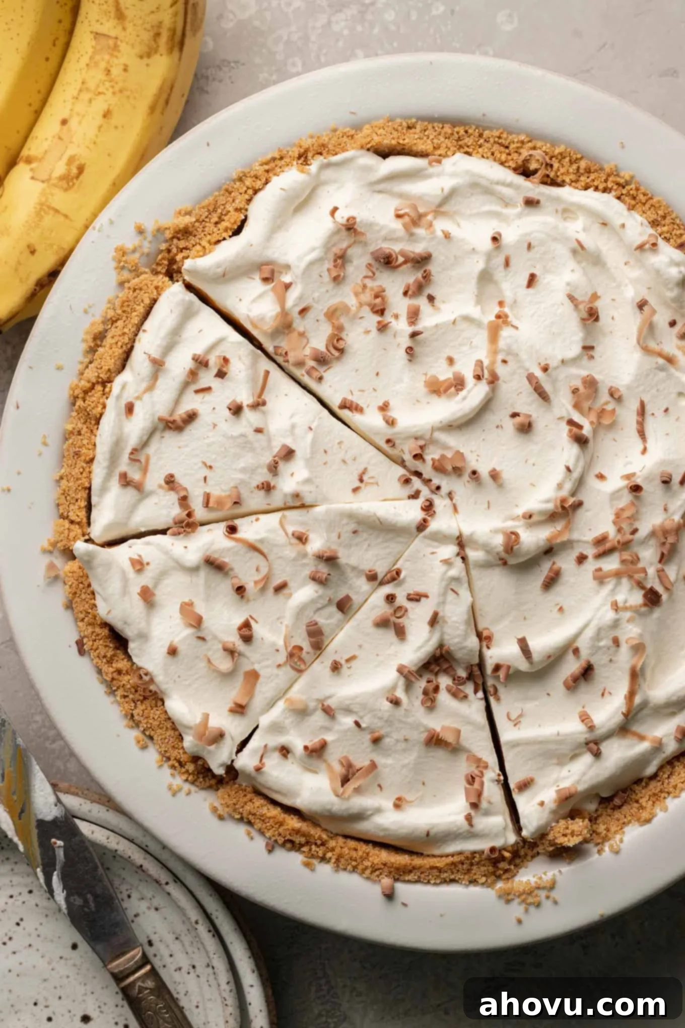An overhead view of a beautifully sliced banoffee pie, revealing its delicious layers, with a few slices already removed from the pie plate. 
