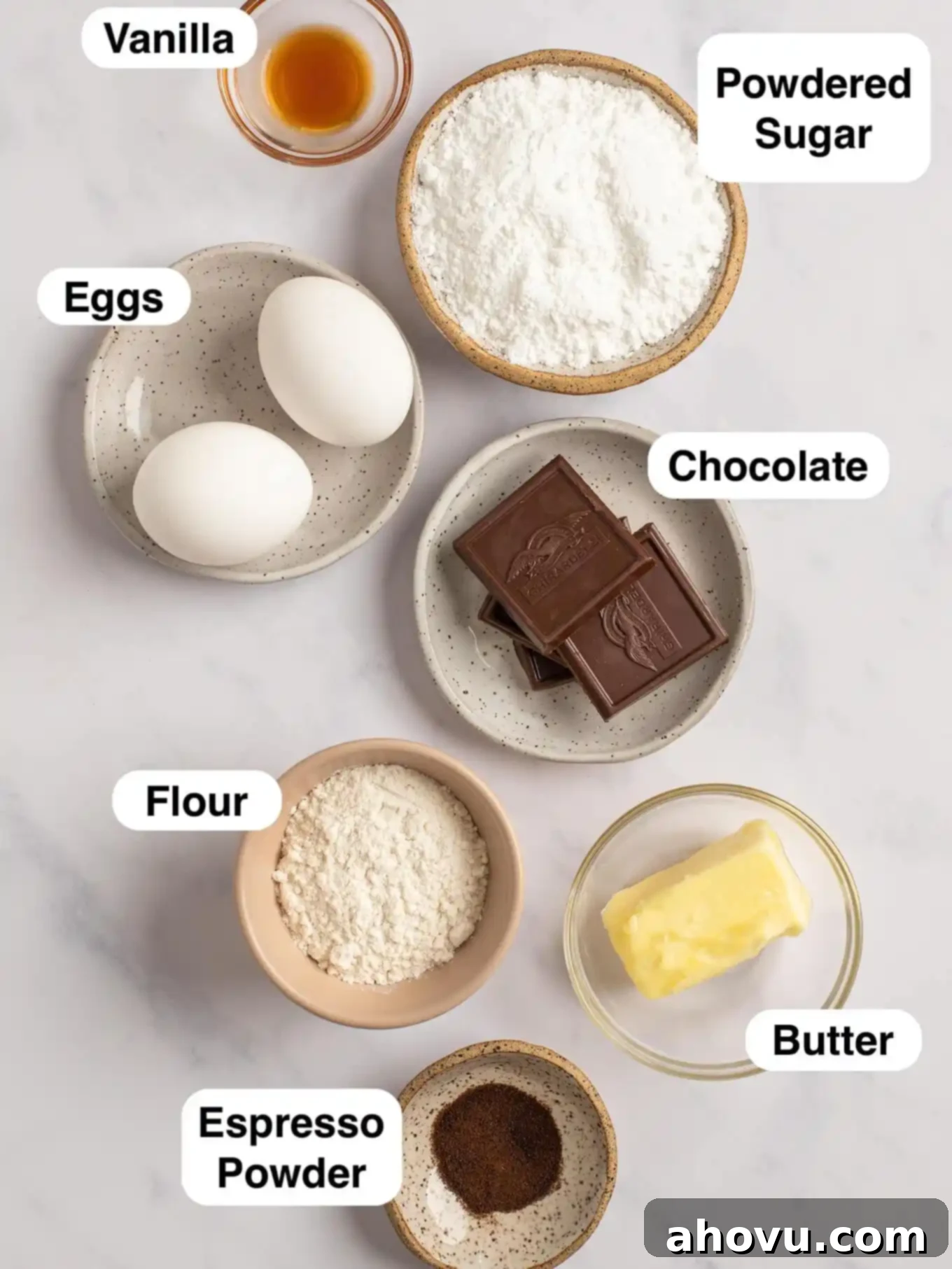 An overhead view showcasing the various essential ingredients laid out neatly for preparing small batch chocolate lava cakes, including butter, chocolate, powdered sugar, eggs, vanilla extract, flour, and espresso powder.