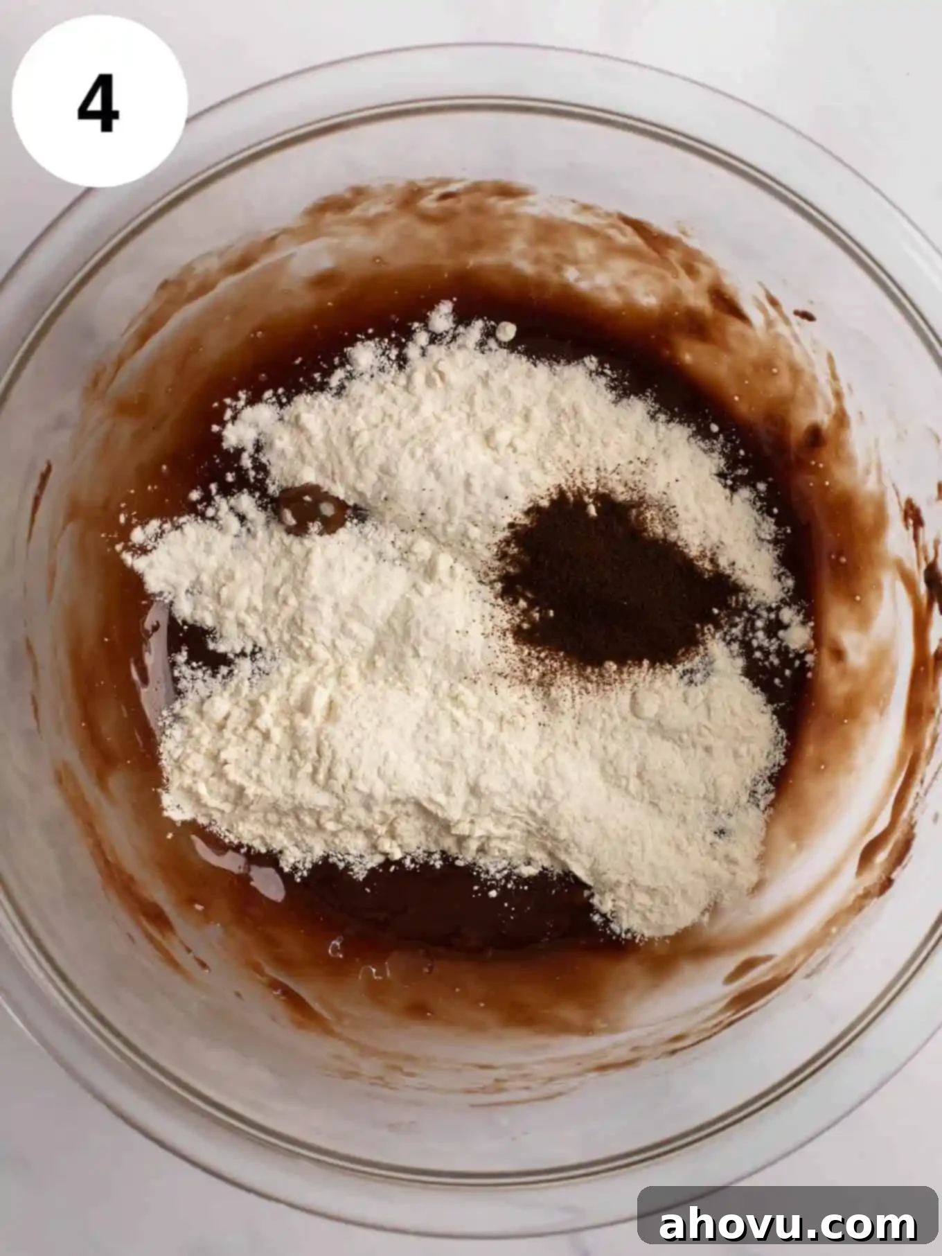 All-purpose flour and instant espresso powder have been added to the chocolate batter in a mixing bowl, awaiting the final gentle mix.