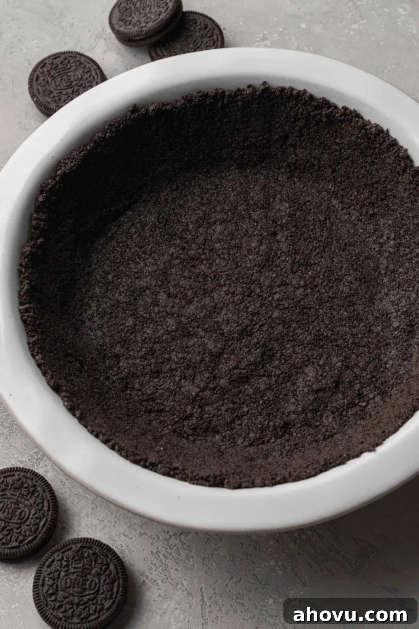 An overhead perspective of a meticulously prepared Oreo pie crust, perfectly pressed into a pristine white pie plate, ready for the delicious filling.
