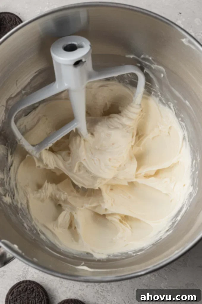 An overhead shot capturing cream cheese, powdered sugar, and vanilla extract being expertly blended together in the bowl of a stand mixer, creating a smooth and creamy base for the filling.