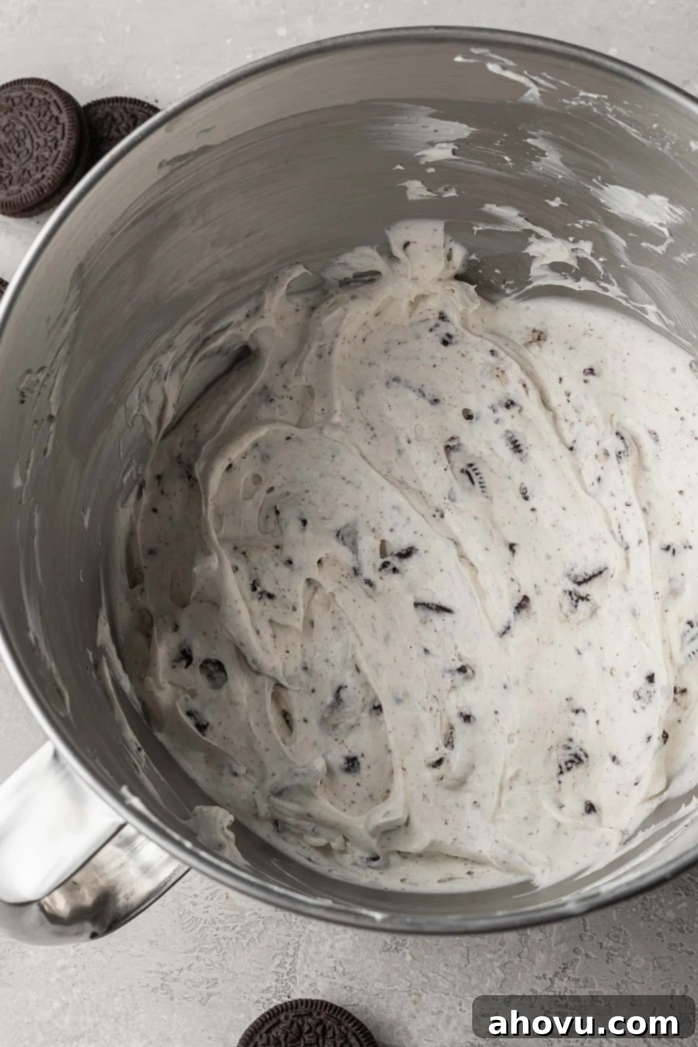A close-up view of the perfectly blended Oreo pie filling, a harmonious mixture of whipped cream and cream cheese, infused with crushed Oreos, glistening in the bowl of a stand mixer, ready to be spread into the crust.