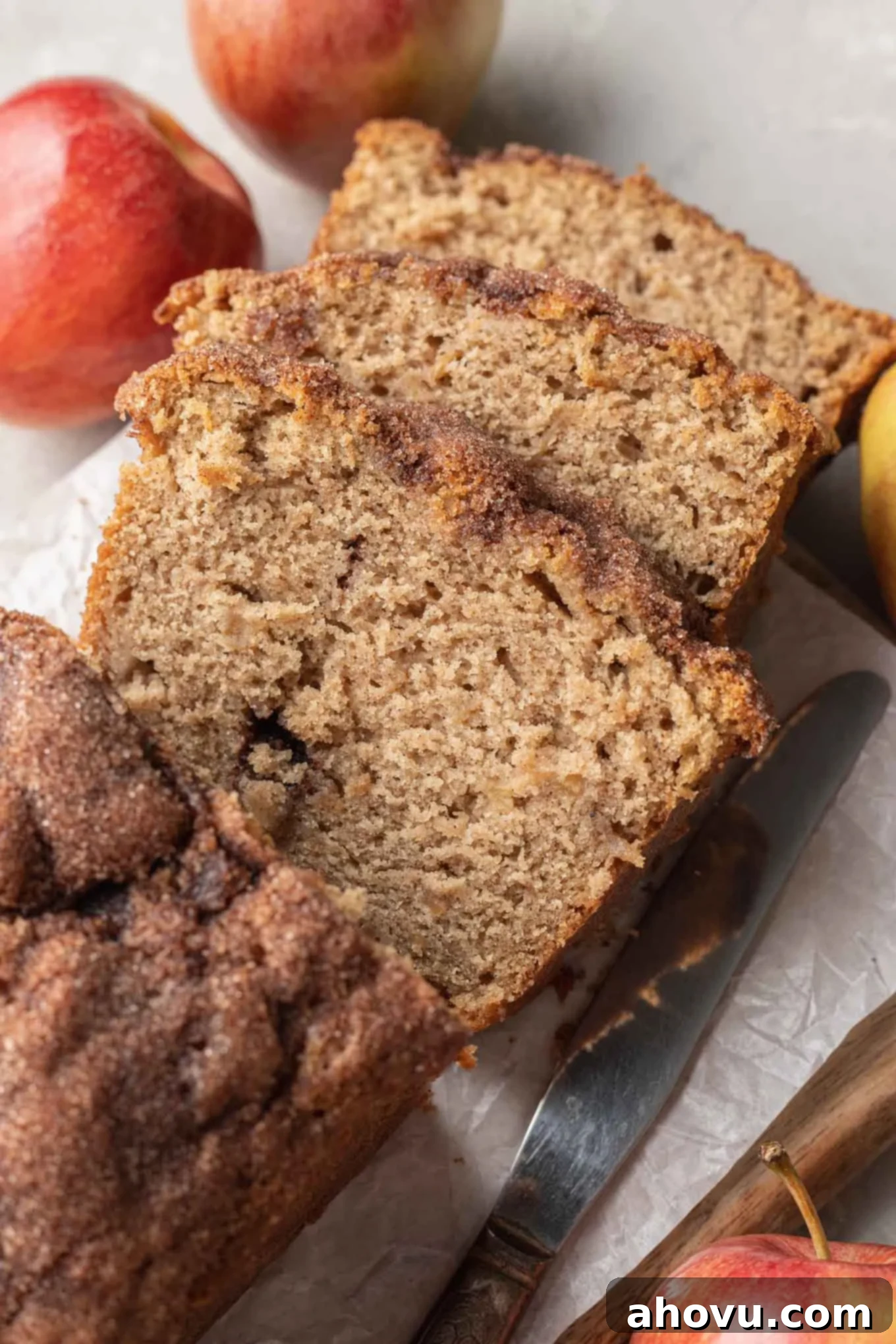 Three slices of apple bread, surrounded by apples. 