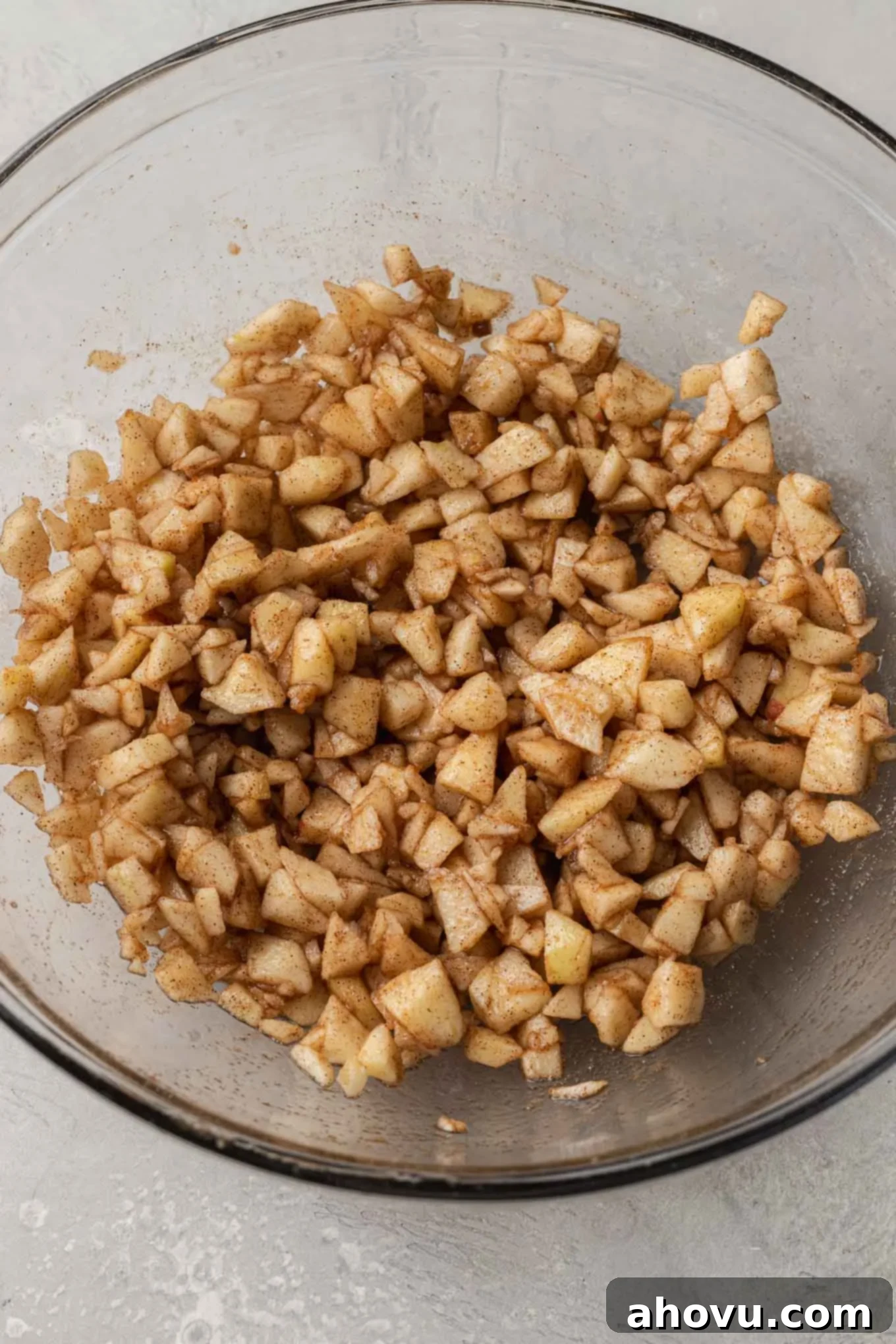 An overhead view of chopped apples in a glass mixing bowl. 