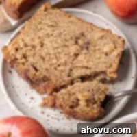 A slice of apple bread on a white speckled plate.
