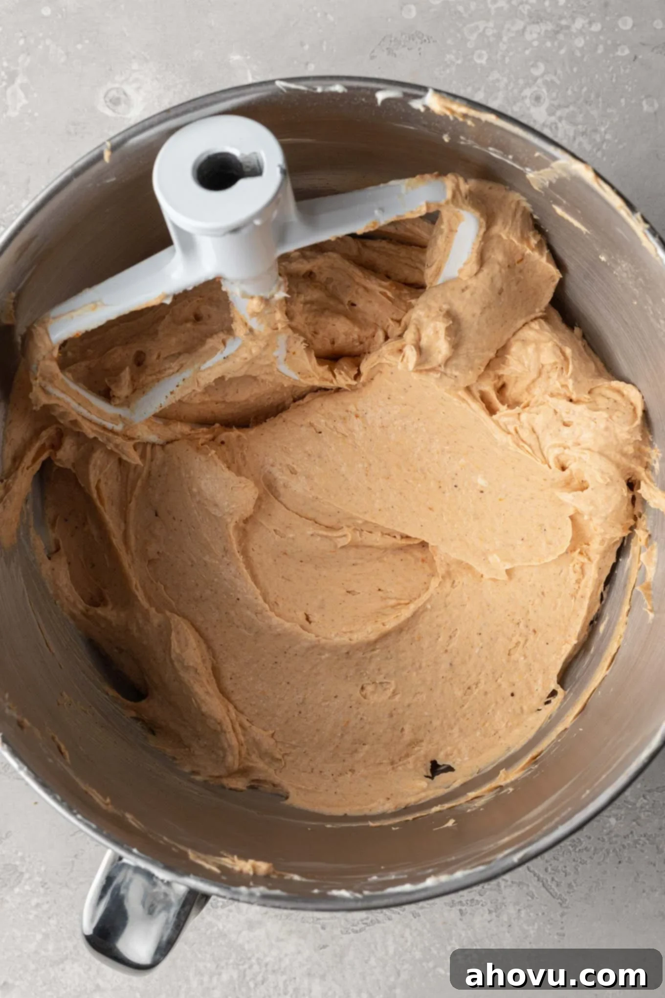 An overhead view of the no-bake pumpkin cheesecake filling, rich and creamy, blended in the bowl of a stand mixer with a paddle attachment.