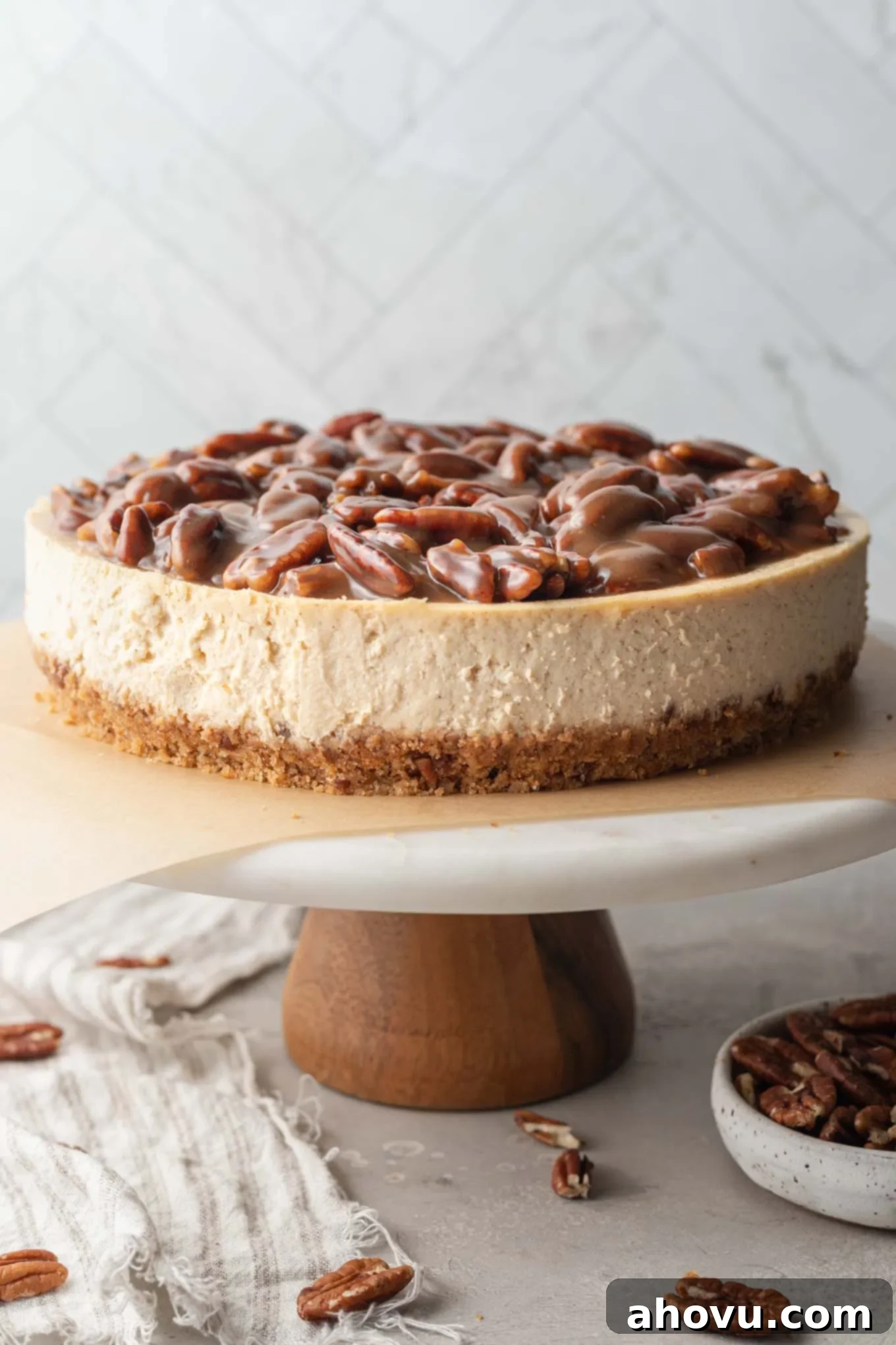 A pecan pie cheesecake on a marble cake stand. 