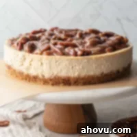 A pecan pie cheesecake sitting on top of a marble cake stand.