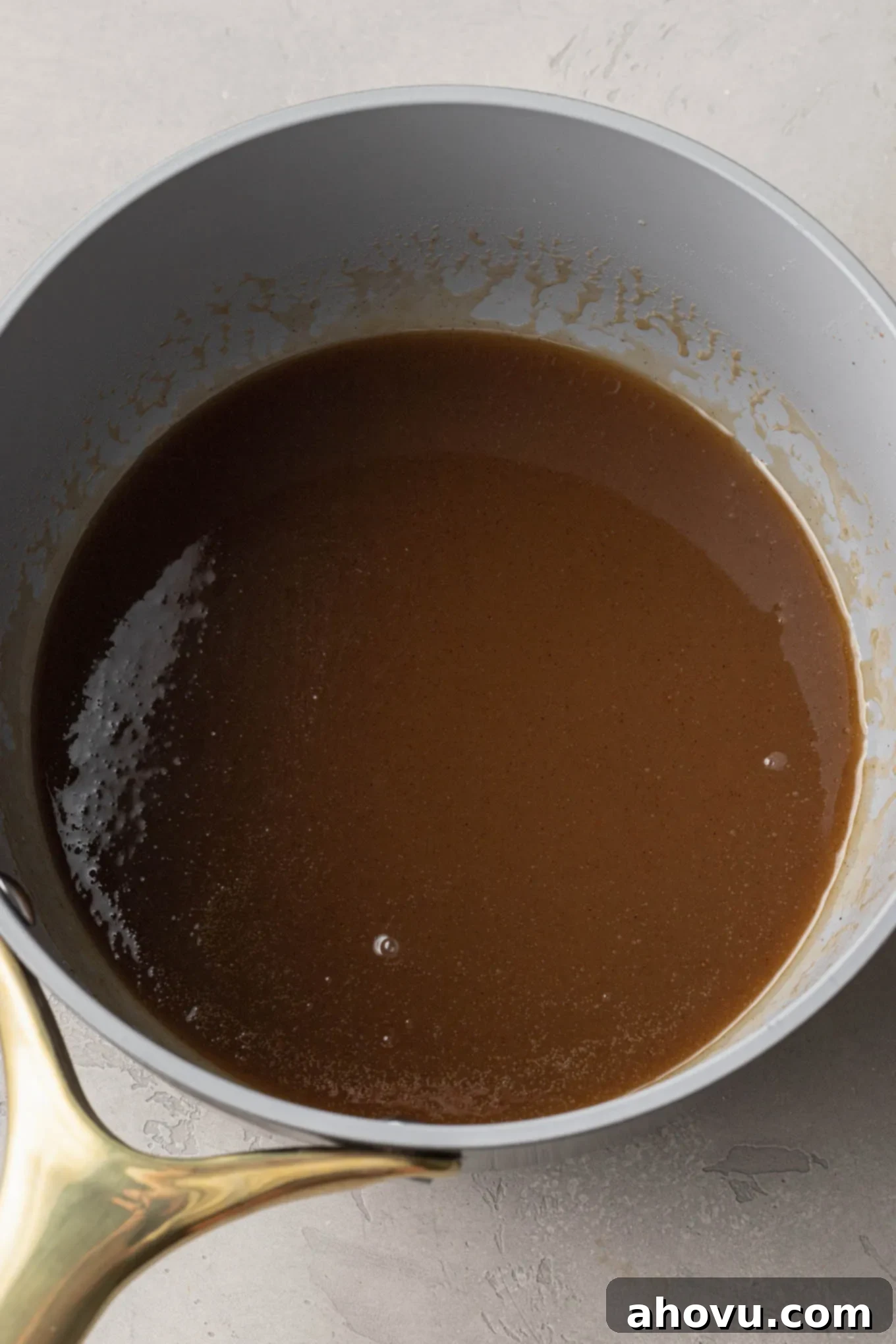 An overhead view of melted cinnamon, butter, and sugar in a saucepan. 