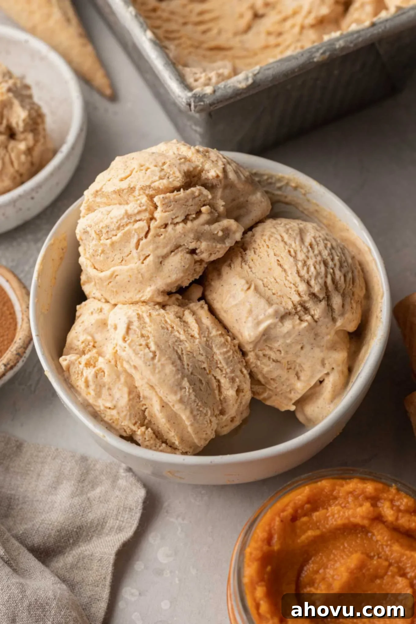 Velvet Pumpkin Swirl 2 Three scoops of homemade pumpkin ice cream in a white bowl.
