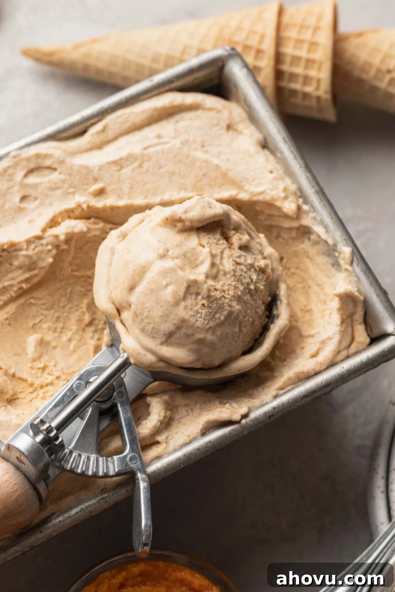 Velvet Pumpkin Swirl 9 Pumpkin ice cream in a loaf pan, being scooped with an ice cream scoop.