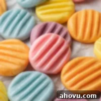 Several pastel cream cheese mints on a piece of parchment paper.