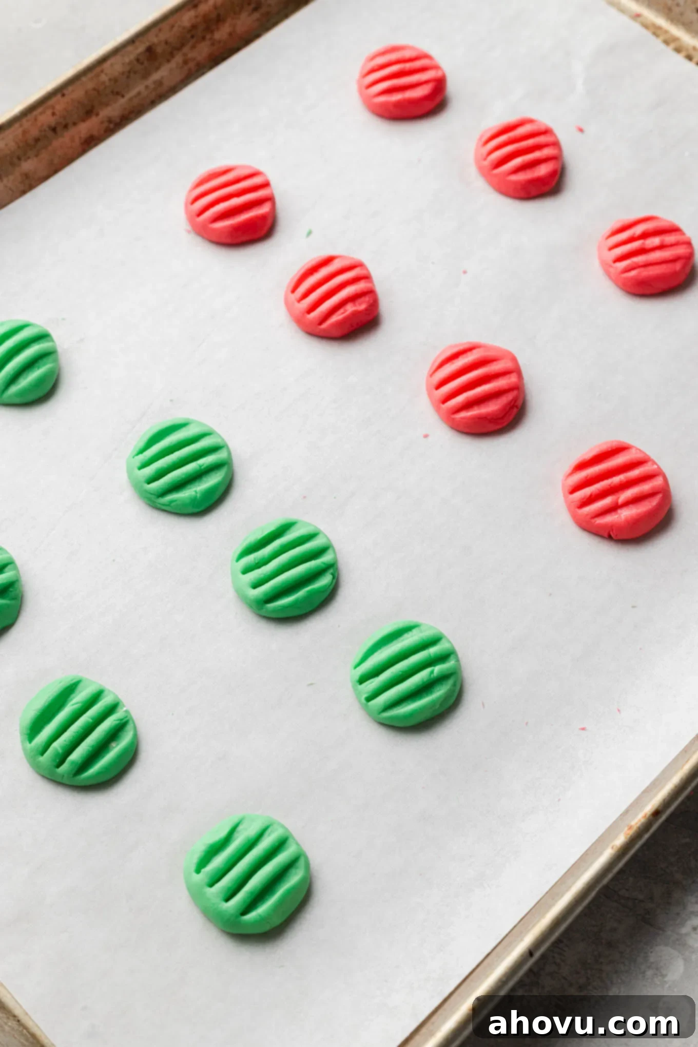 Creamy Dream Mints 9 Red and green cream cheese mints drying on a parchment paper-lined baking sheet after being shaped and indented with a fork.