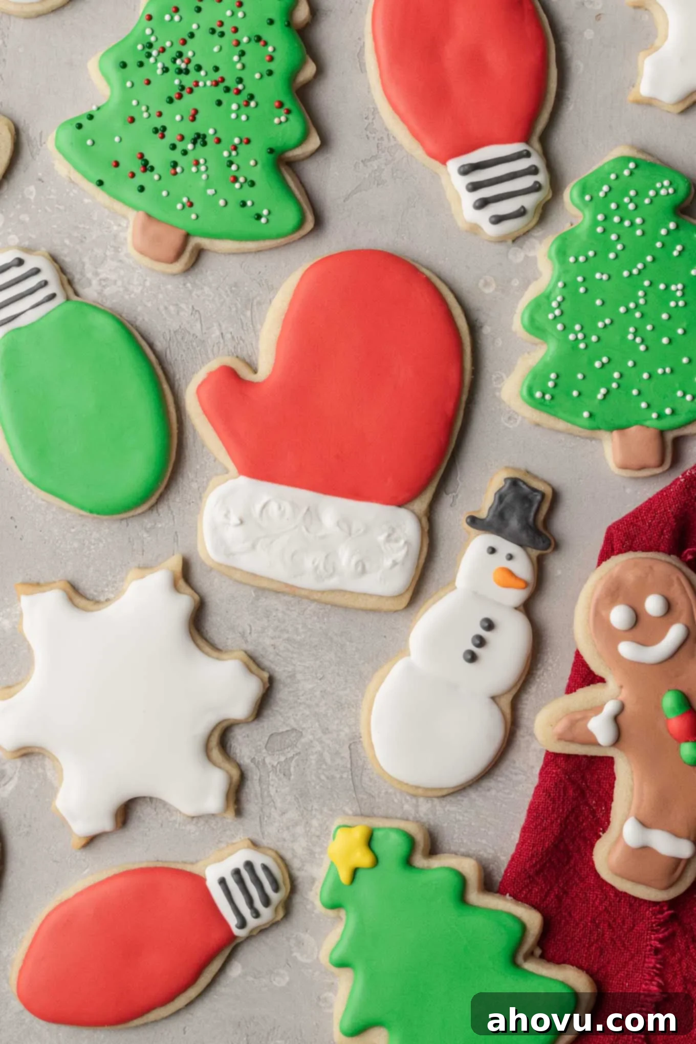 A festive collection of Christmas sugar cookies intricately decorated with vibrant royal icing, presented on a chic gray surface.